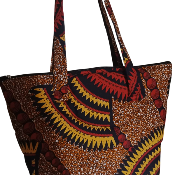 Upgrade your daily carry with our African Print Zip-Top Tote. Perfectly balancing functional design with high-impact aesthetics, this bag takes you from morning meetings to weekend brunch without missing a beat. Product Features: Secure Closure: Durable top zipper to keep your essentials safe. Spacious Design: Roomy interior for your laptop, makeup bag, and daily essentials. Sturdy Straps: Reinforced shoulder straps for comfortable all-day wear. Premium Fabric: 100% authentic African Wax Print (Ankara) with a structured lining.